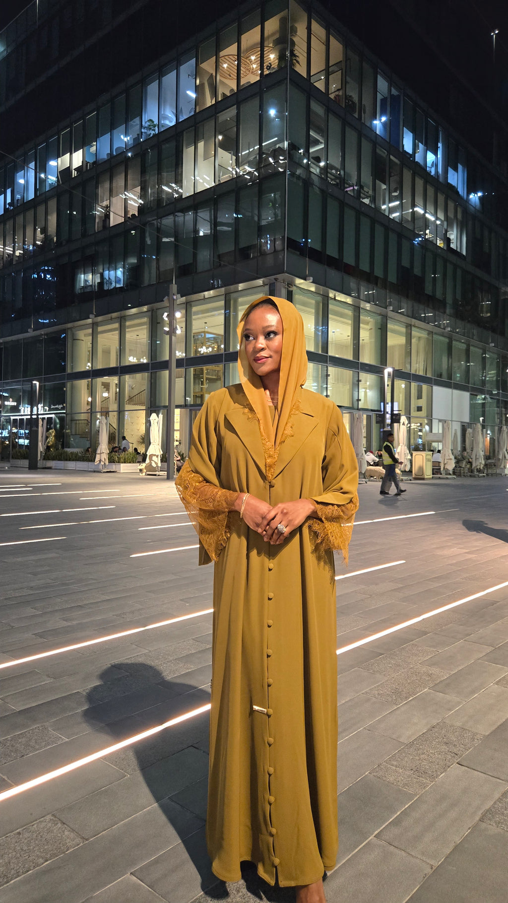 Woman in a yellow dress standing on a city street at night.